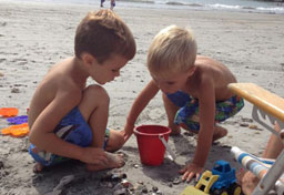 Two small boys play with sand toys